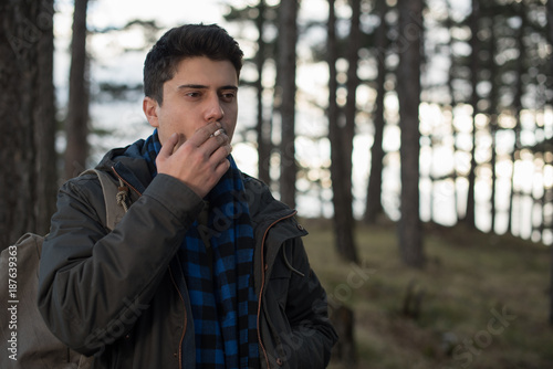 young man smoking cigar in forest 
