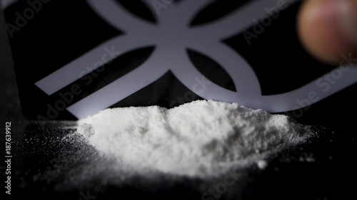 DRUGS: Man does a lines of heroin by plastic card - Close up. Plastic card and white powder. Lines and pile of cocaine on wooden table. Macro photo