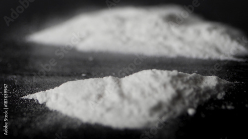 DRUGS: Man does a lines of heroin by plastic card - Close up. Plastic card and white powder. Lines and pile of cocaine on wooden table. Macro photo