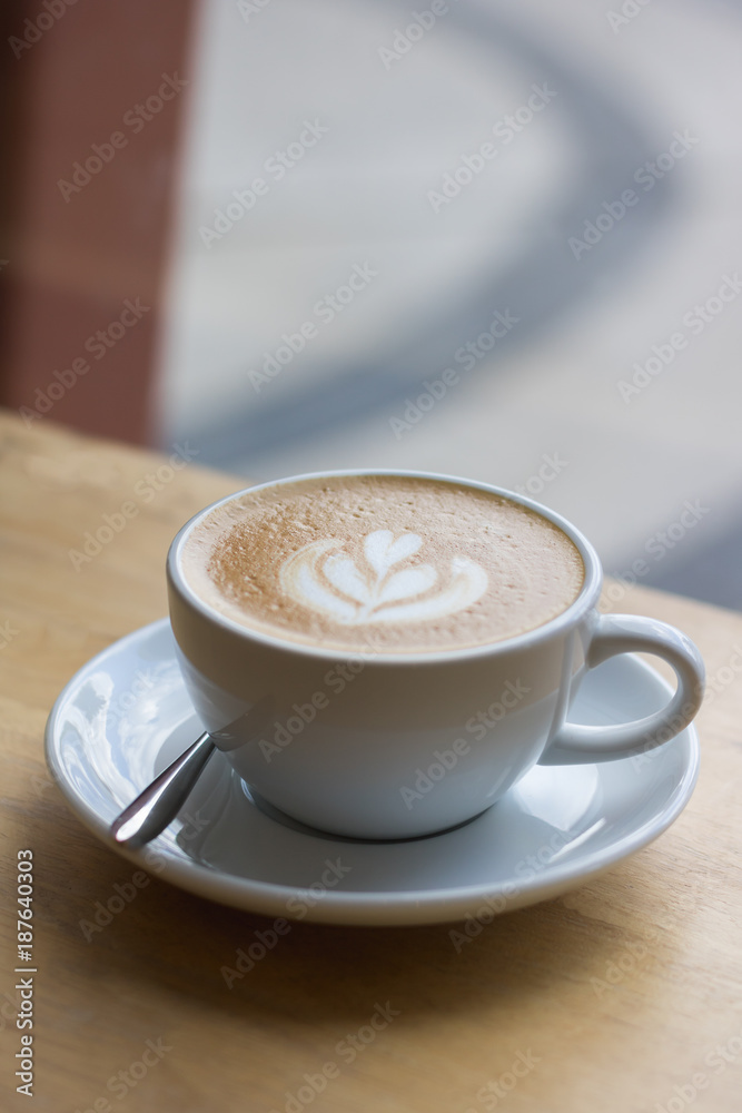 Hot coffee latte with beautiful foam art on glass table.Indoor cafe Hot coffee latte with beautiful foam art on glass table.Indoor cafe