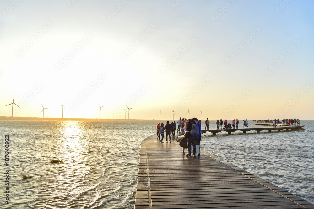 Fototapeta premium Tourists on a Wooden Walkway at Gaomei Wetlands in Taichung