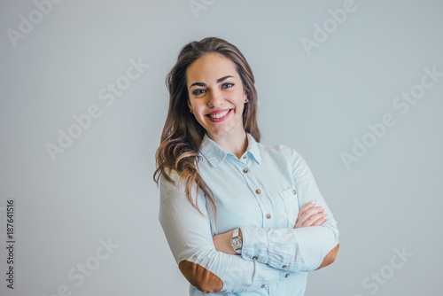 Successful young business woman with hands folded, smiling.