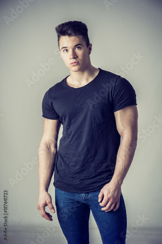 Handsome young muscular man looking at camera in studio shot over neutral background