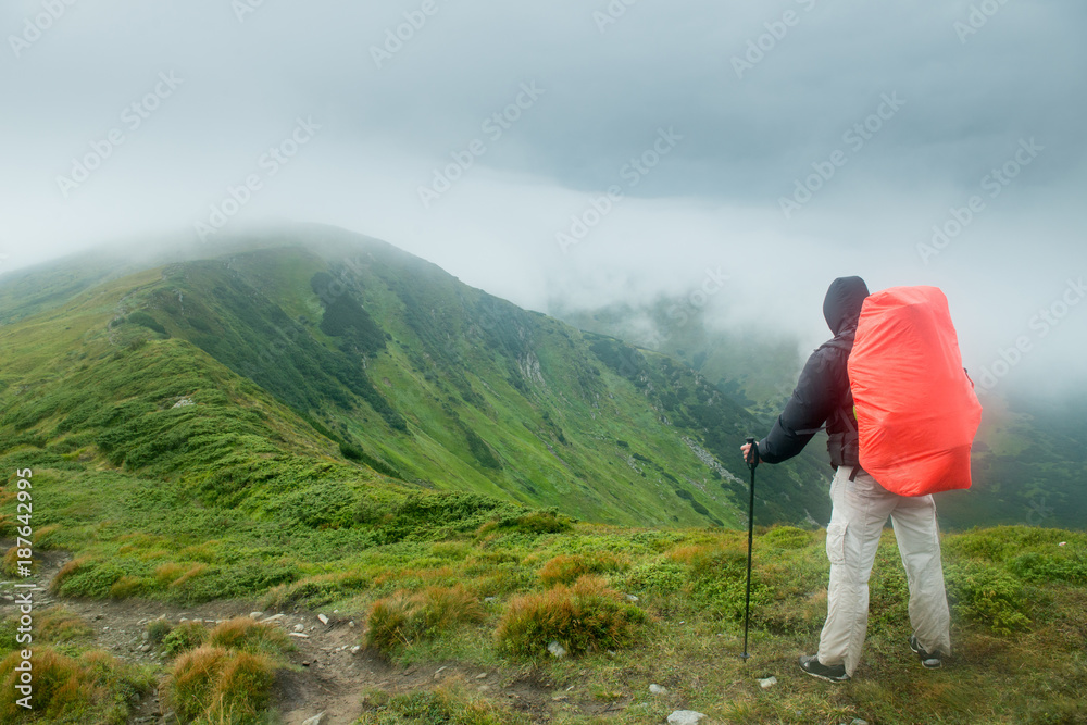 Traveler with backpack in the mountains in the clouds