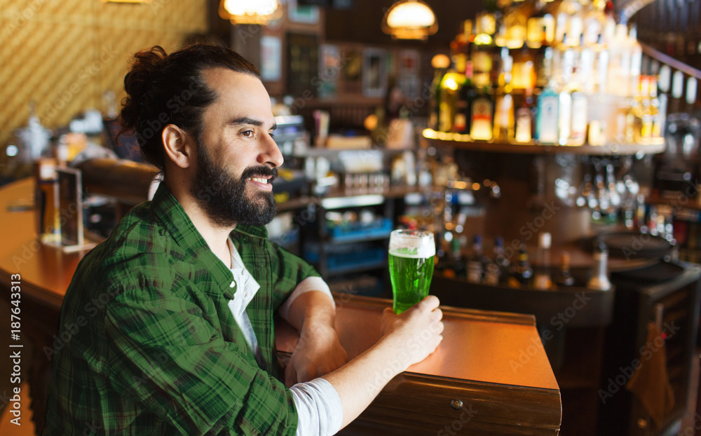 man drinking green beer at bar or pub