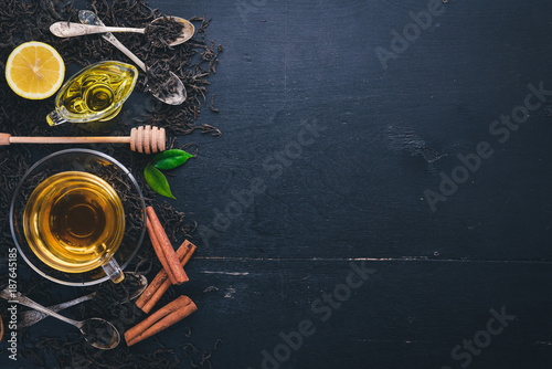 Tea in a glass cup with spices and herbs. On a black wooden background. Top view. Copy space.