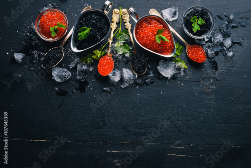 Spoon with black and red caviar on a wooden background. Top view. Free space for text.