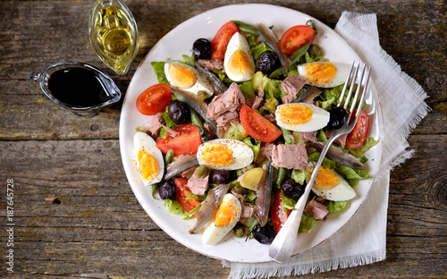 French salad Nicoise with tuna, boiled potatoes, egg, green beans, tomatoes, dried olives, lettuce and anchovies.