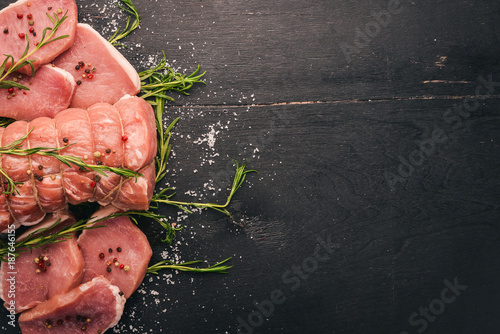 Raw meat Beef fillet with rosemary and spices on a black wooden background. Top view. Free space for text