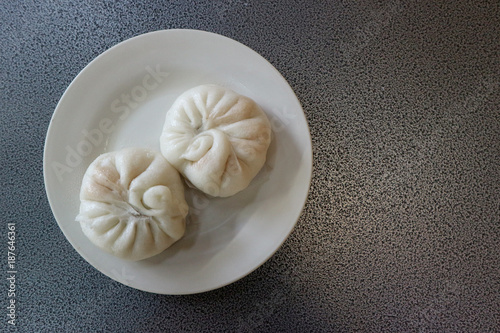 two chinese steamed buns or dumpling on dish with copy space background.