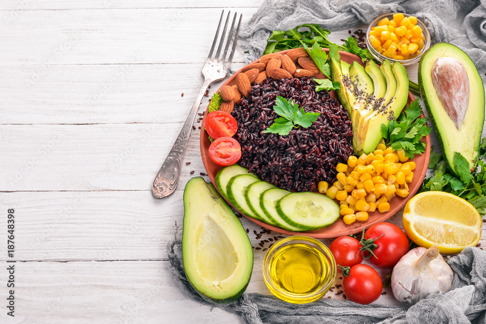 Black rice, avocado, cucumber, corn and almonds. On a wooden background. Top view. Free space for your text. Black rice, avocado, cucumber, corn and almonds. On a wooden background. Top view. Free space for your text.