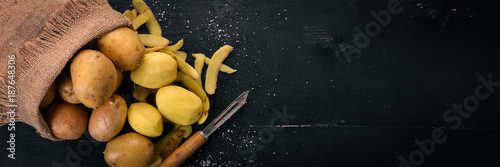 Fotografie Raw potatoes on a black wooden background