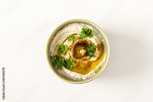 Vegetarian snack. Hummus with greens, dressed with olive oil and paprika in a ceramic plate. Dark background. Traditional Middle Eastern cuisine. 