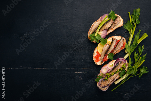 A set of sandwiches with sprats, and caviar, onion and parsley, on a wooden background. Top view. Copy space.