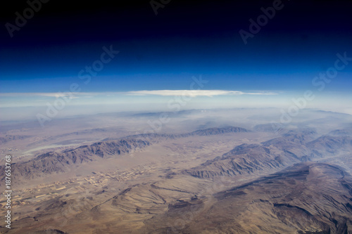 View of a mountainous hilly terrain from space  or from a window of an airplane . Fields in the form of squares from a great height. Travel  flight by plane.