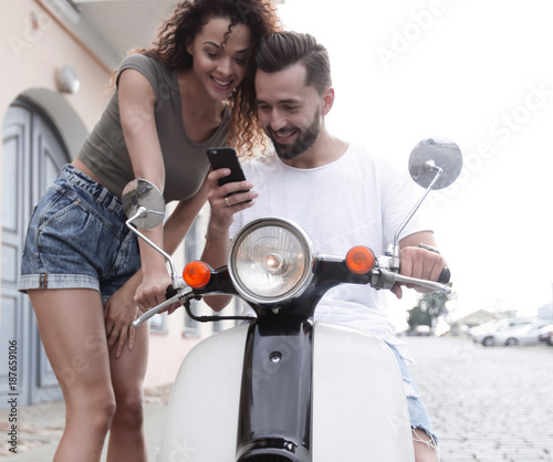 Happy young couple having summer trip on a scooter