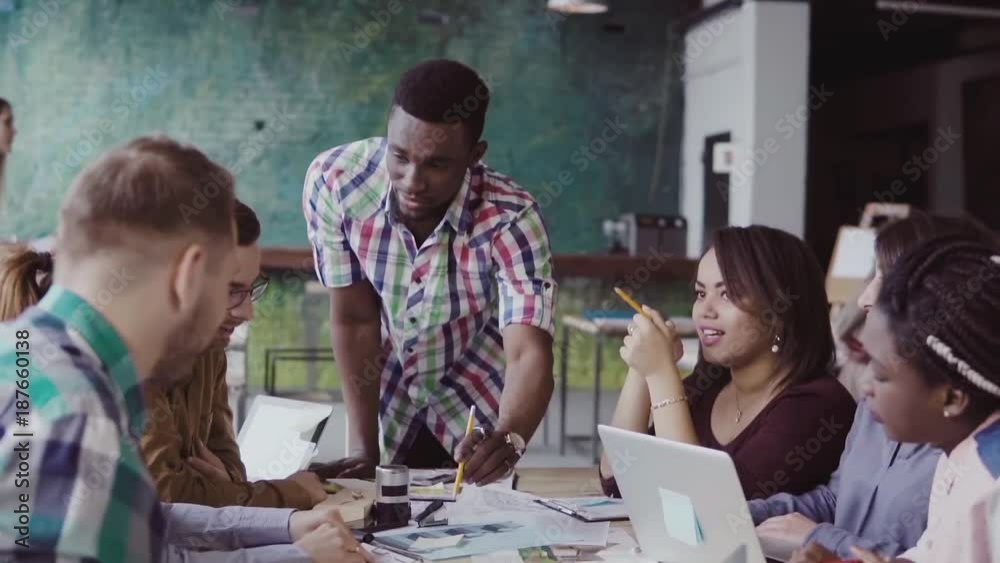 Young multiracial group of people working in coworking space. Small start-up of architects discussing the project ideas.