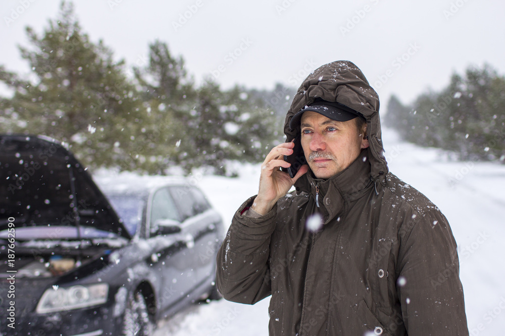 driver in the winter on the road calls for help by phone driver in the winter on the road calls for help by phone