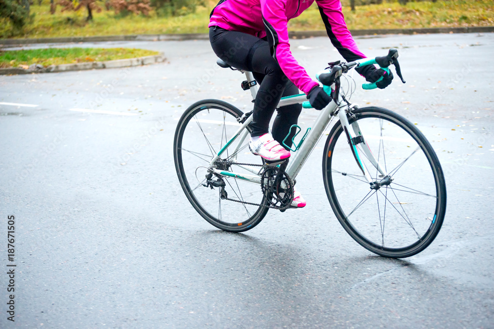 Young Woman in Pink Jacket Riding Road Bicycle in the Park in the Cold Autumn Day. Healthy Lifestyle. Young Woman in Pink Jacket Riding Road Bicycle in the Park in the Cold Autumn Day. Healthy Lifestyle.