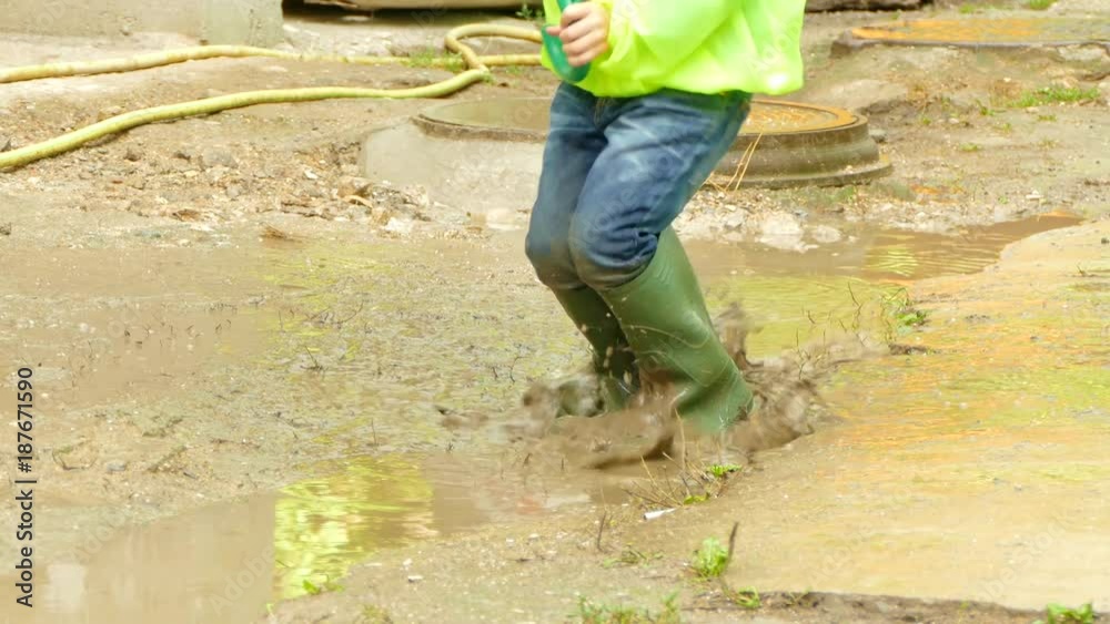 boy with an umbrella jumping in a puddle boy with an umbrella jumping in a puddle
