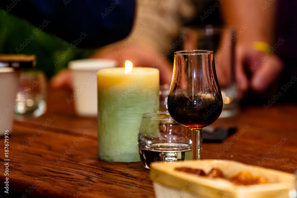 The bartender pours the liqueur into the glass and heats it in the candle. The bartender pours the liqueur into the glass and heats it in the candle.