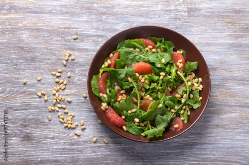 Fresh salad from arugula with grapefruit and pine nuts on a wooden background. Healthy delicious food