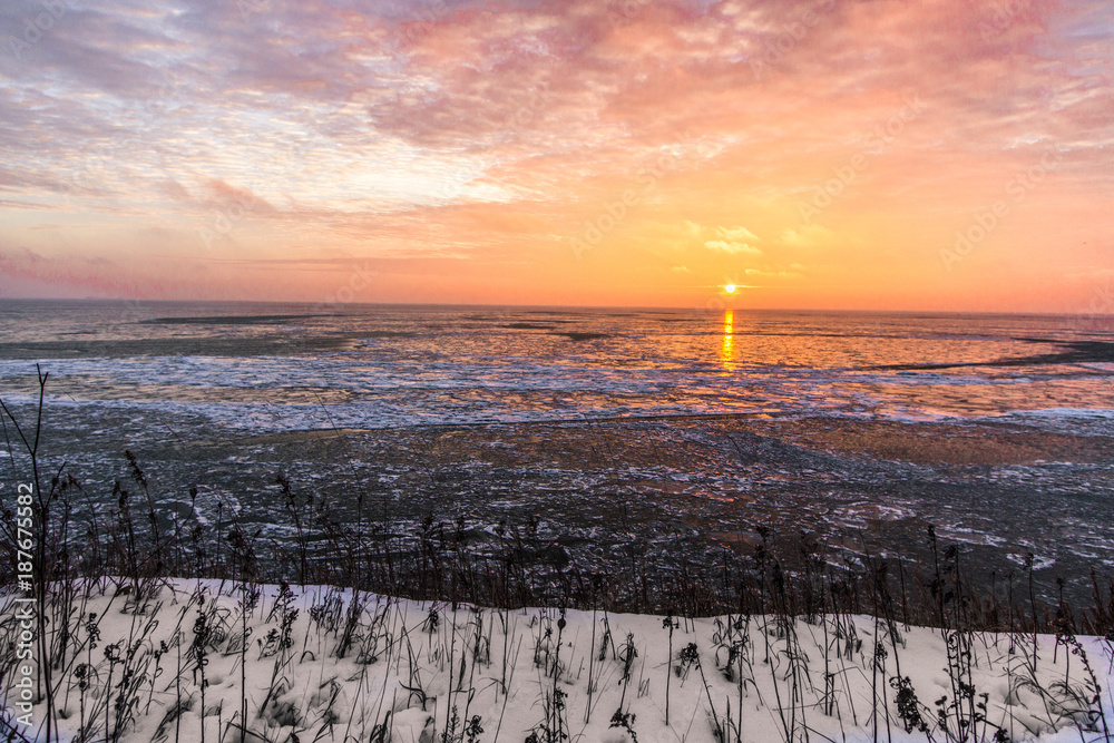 Frozen Great Lakes Sunrise. Scenic sunrise reflection over the icy Great Lakes horizon on the coast of Lake Huron from an overlook in Port Sanilac, Michigan. Frozen Great Lakes Sunrise. Scenic sunrise reflection over the icy Great Lakes horizon on the coast of Lake Huron from an overlook in Port Sanilac, Michigan.