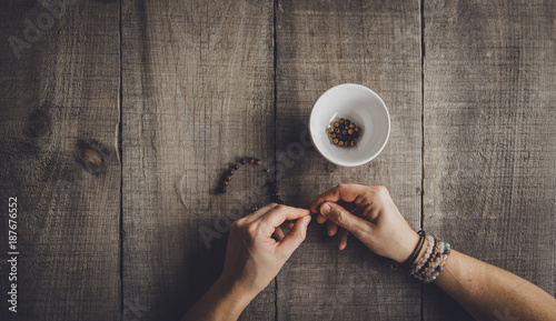 Cropped hands of woman making bracelets at table