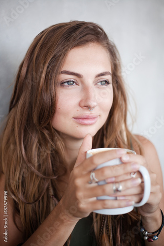 Portrait of beautiful girl drinking is holding a white mug with some drink