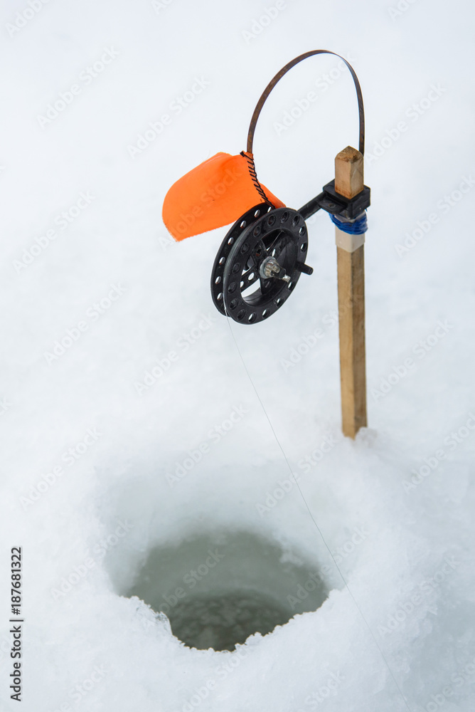 Winter fishing rod and ice hole close up, tip-up with reel and