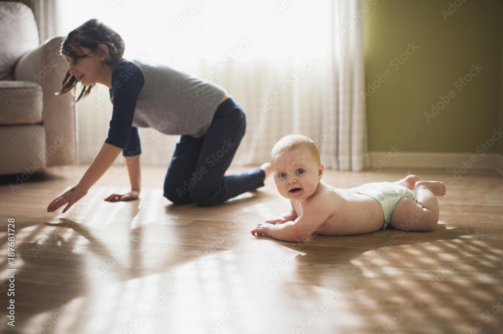 Portrait of cute brother lying on floor while sister crawling in background at home Portrait of cute brother lying on floor while sister crawling in background at home