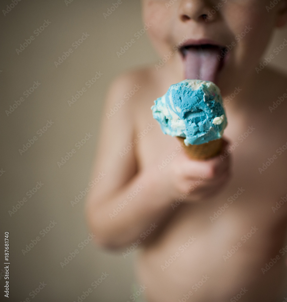 Midsection of shirtless boy licking ice cream while standing against wall at home Midsection of shirtless boy licking ice cream while standing against wall at home