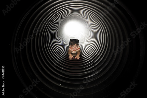 Portrait of playful boy lying in huge metallic pipe