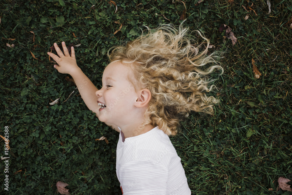 High angle view of cheerful girl lying on grassy field at park High angle view of cheerful girl lying on grassy field at park