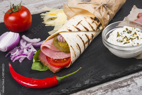 Burito with ham, tomatoes and jalapeno pepper.
