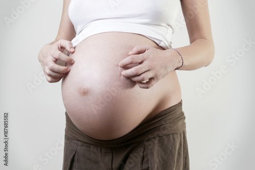 Pregnant woman scratches her belly