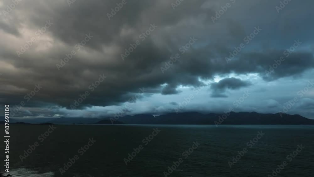 Ocean waves lapping across the south china sea with mountains and cloudy dramatic skies high definition time lapse movie footage.