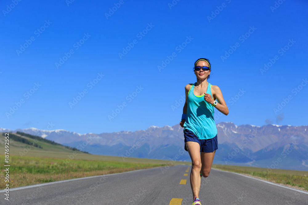Young fitness healthy lifestyle woman runner running on road with snow capped mountains in the distance