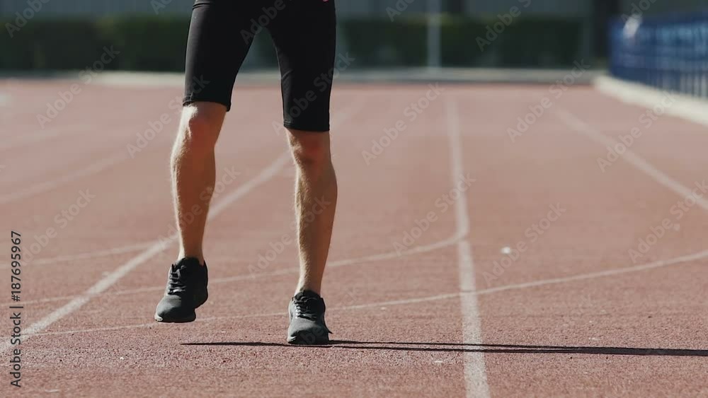 Sportsman warming up leg muscles at stadium for better blood circulation Sportsman warming up leg muscles at stadium for better blood circulation