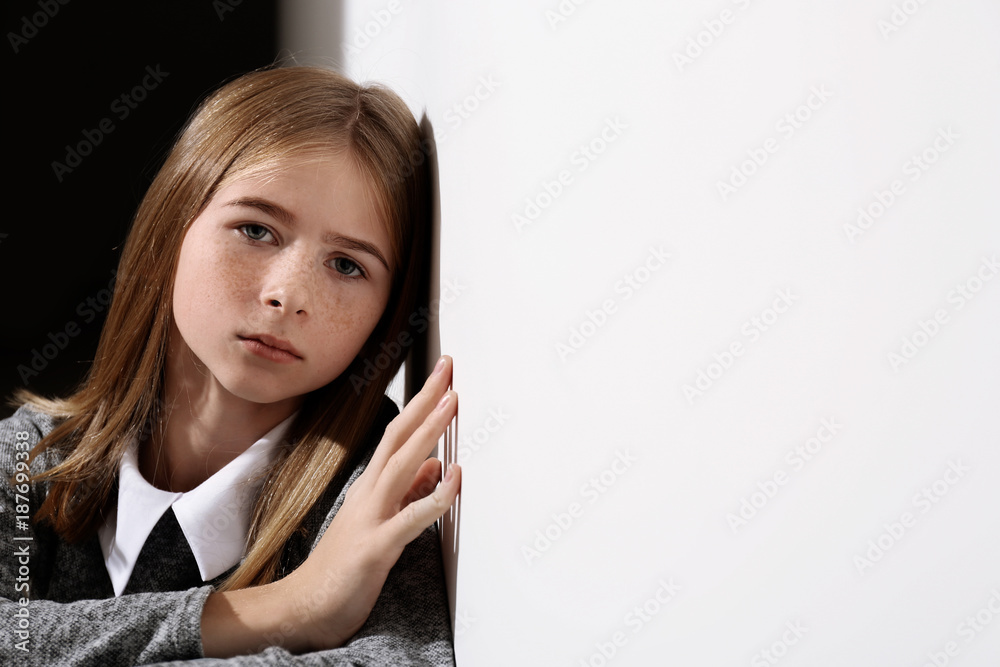Sad teenage girl leaning against wall indoors Sad teenage girl leaning against wall indoors