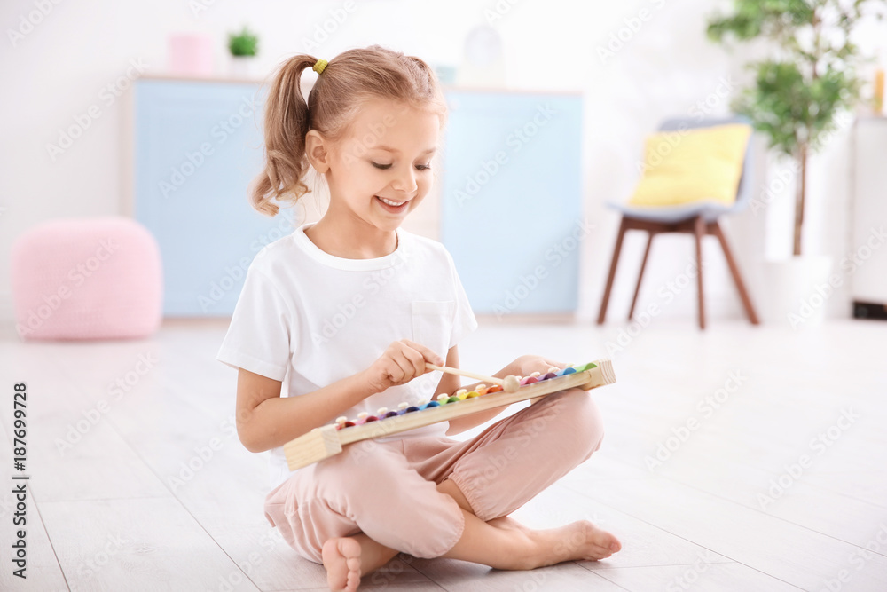 Cute little girl playing with xylophone  at home