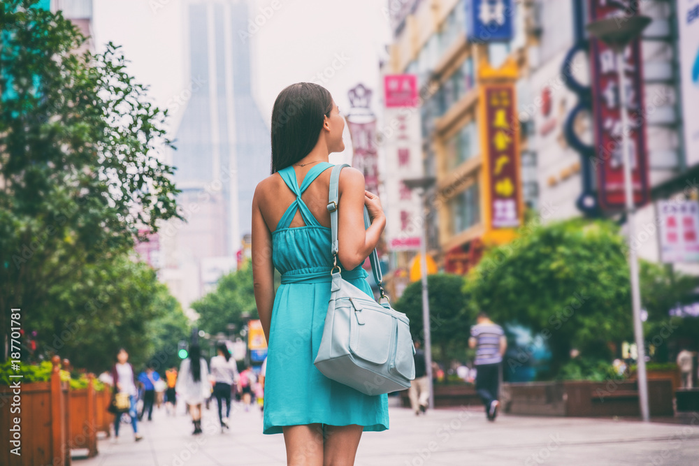 Naklejka premium Szanghaj miasto zakupy styl życia kobieta spaceru na ulicy sklepowej Nanjing Road, Chiny, Azja. Azjatycka dziewczyna z torebką na miejskiej przygodzie, słynnej chińskiej atrakcji.