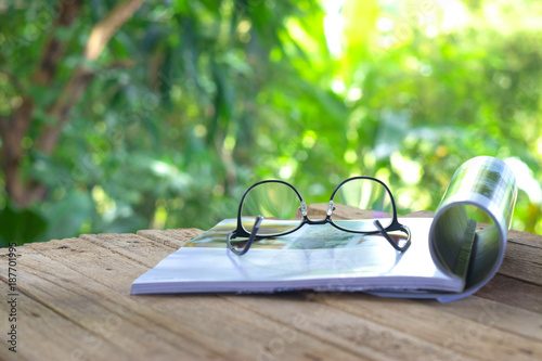 An open book, glasses and a blanket on the wooden background. orange, coffee cup, sunlight, selective focus.