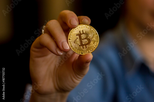 Woman holding a golden bitcoin physical coin