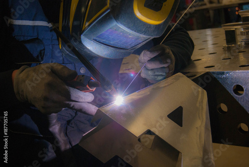 Fotografía man in concentrate on welding tig mode an aluminium letter