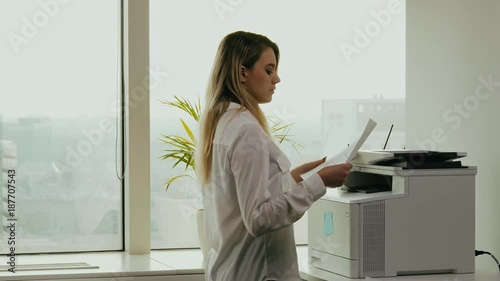 young businesswoman prints on the printer in the office