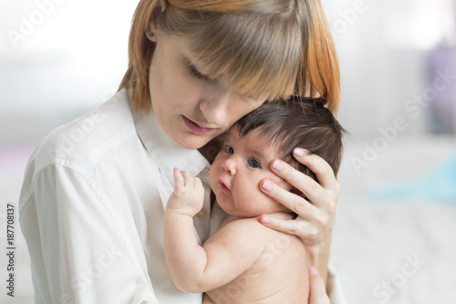 Careful mother hugging her baby daughter