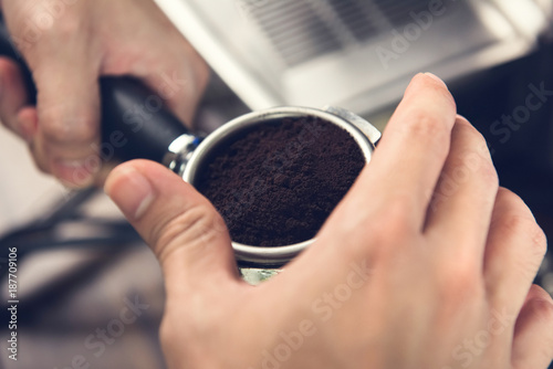 Hands of barista holding portafilter with ground coffee