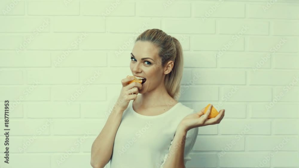 young blonde caucasian woman in her late 20` joking around in front of a white brick wall background and modeling with different acessories and fruits young blonde caucasian woman in her late 20` joking around in front of a white brick wall background and modeling with different acessories and fruits