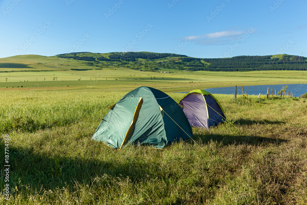 Two tents in a meadow near the water, landscape. Two tents, a landscape.journey to Georgia